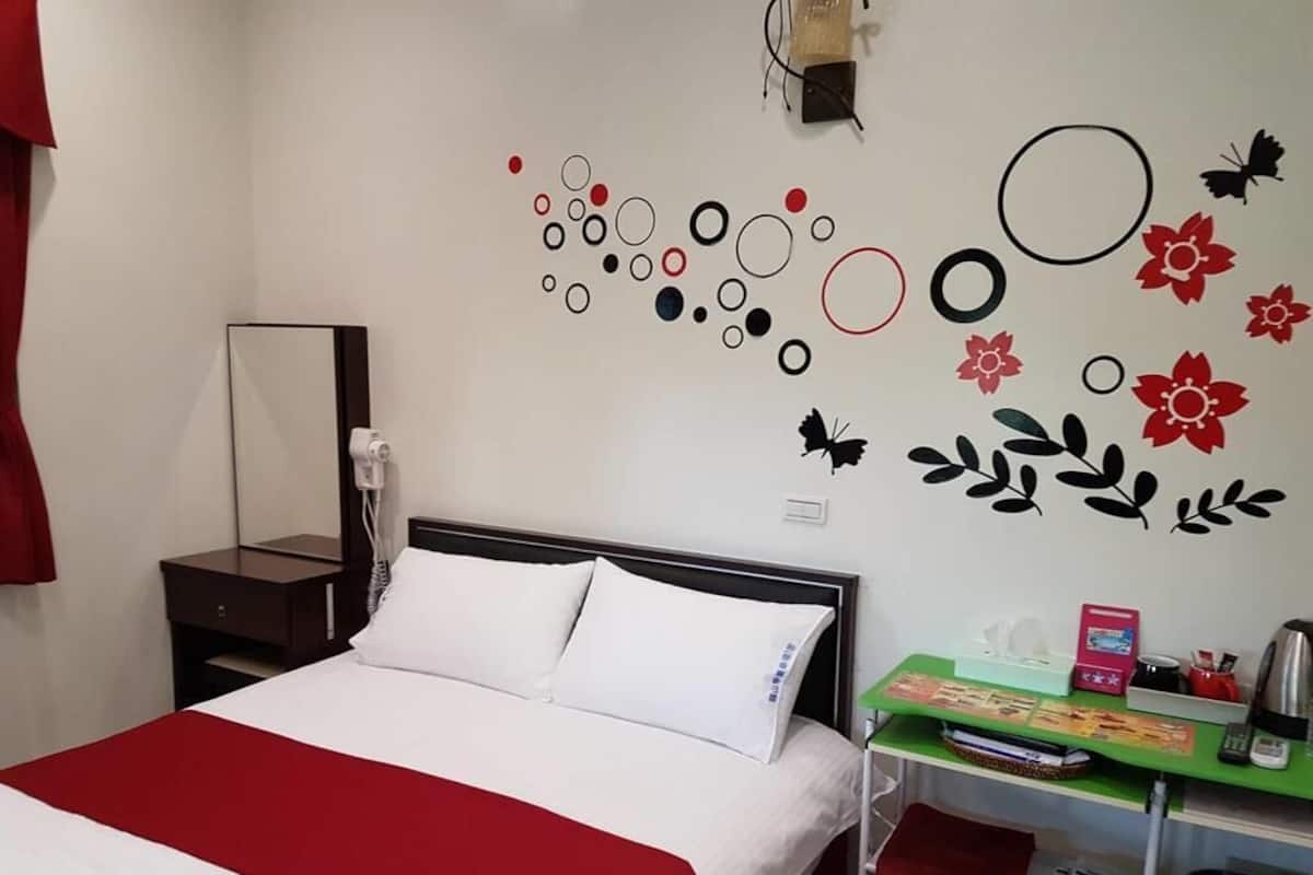 Une chambre d’hôtel équipée d’un lit, d’un bureau et d’un mur décoré de motifs circulaires et floraux.