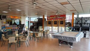 Una sala de billar con mesas, sillas y una mesa de billar.