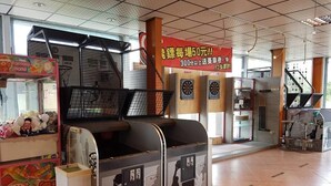 Bolera con un cartel que indica una tarifa de 50 yenes por carril, un contenedor de basura y una máquina expendedora.