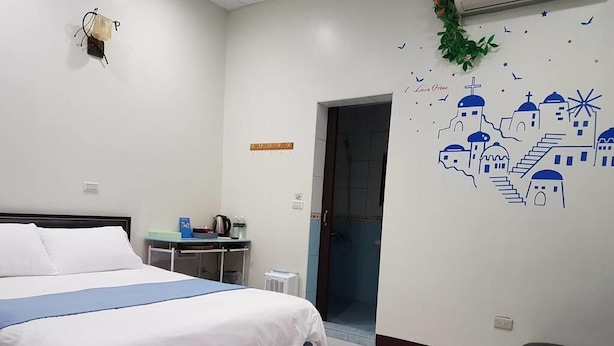 Un dormitorio con cama, escritorio y decoración en la pared.