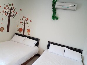 Dos camas con ropa de cama blanca, un aire acondicionado de pared y un adhesivo mural con ilustraciones de animales.