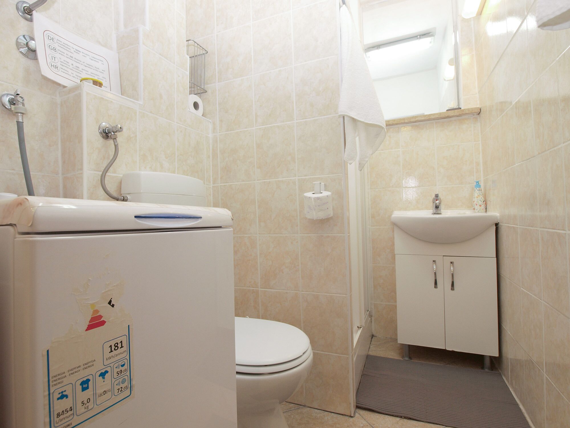 Een badkamer met toilet, wastafel, douche en een boiler.