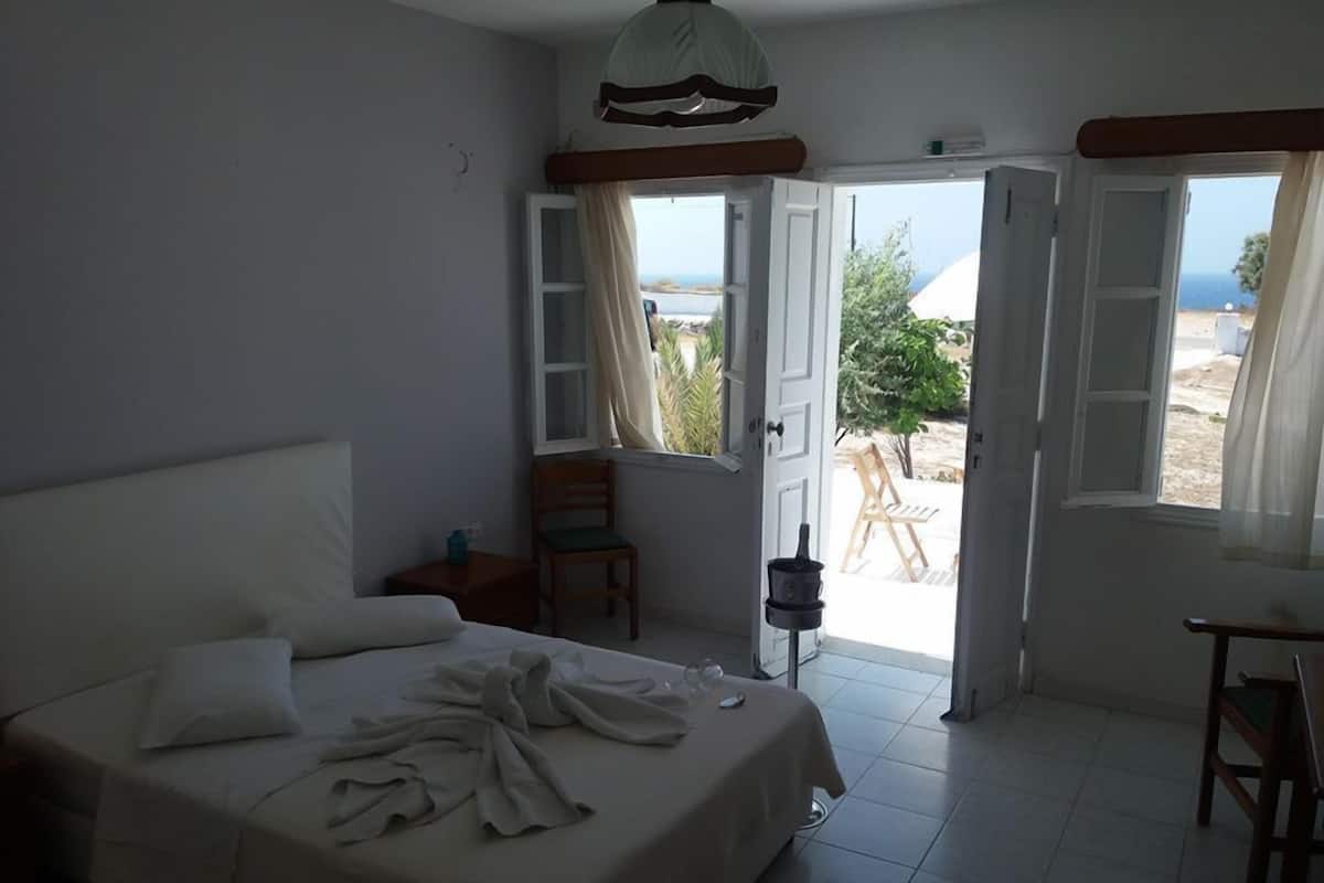 Un dormitorio con cama, una silla, una mesa y vistas al exterior.