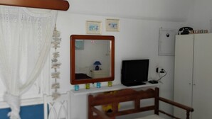Un dormitorio con cama, escritorio con computadora, armario y espejo.