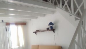 A living room with a white staircase, a beige sofa, and a white coffee table. - Abyssanto Villa (Santorini)