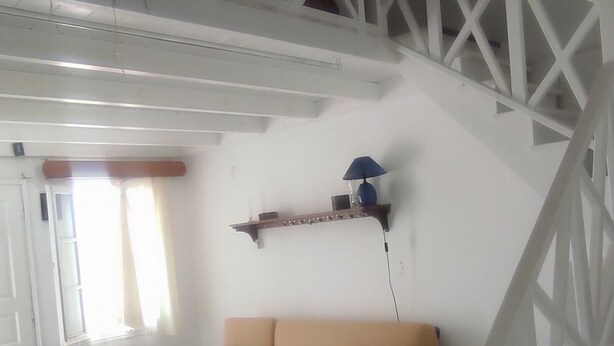 Una sala de estar con una escalera blanca, un sofá color beige y una mesa de centro blanca.