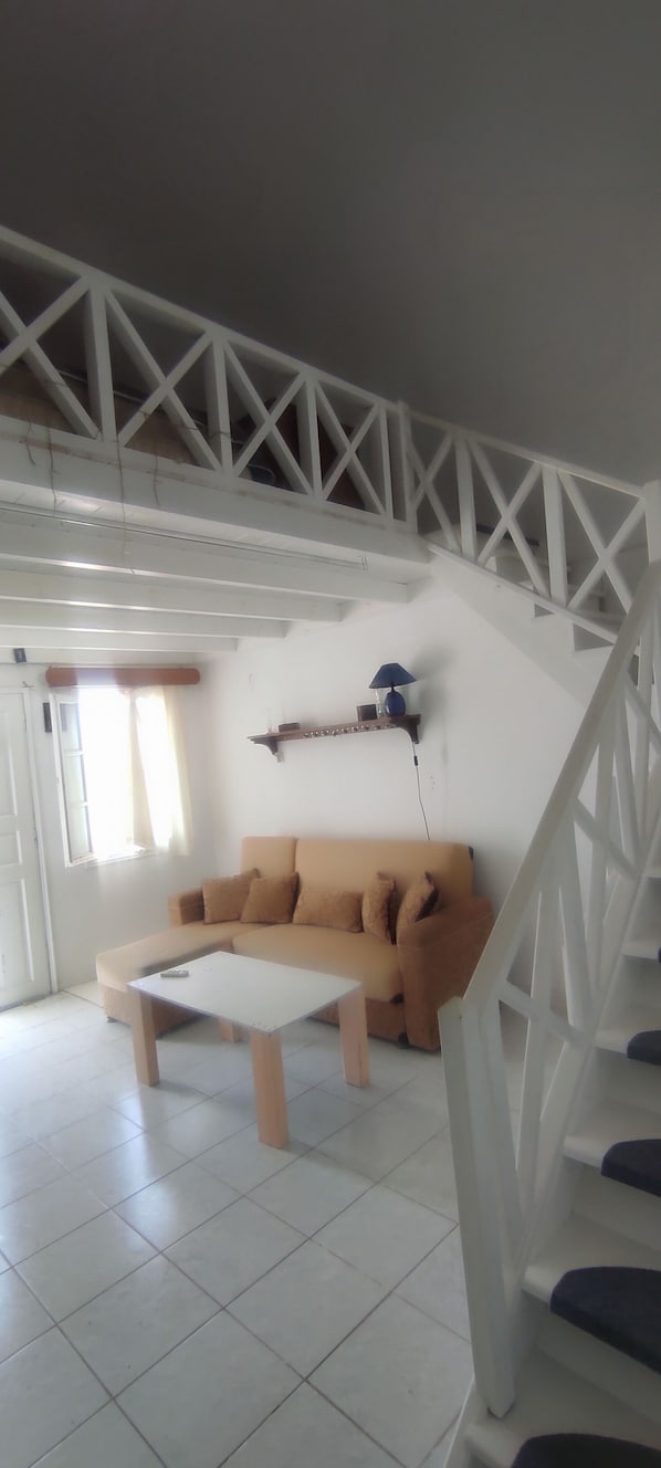 A living room with a white staircase, a beige sofa, and a white coffee table. - Abyssanto Villa (Santorini)