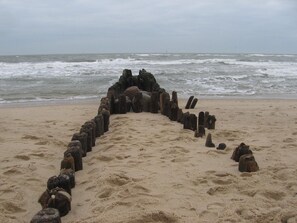A sandy beach with a circle of wooden posts arranged in a semi-circle. - Dorotheenhof (St. Peter-Ording)
