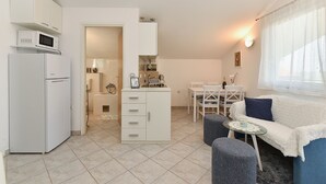 A compact living space with a kitchenette, a dining area, and a seating area with a sofa and ottoman. - Apartment 1860/22683 (Istria - Medulin), 1500m from the beach (Medulin)