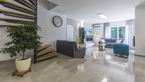 A modern living room with a staircase, a large potted plant, a grey sofa, a blue sofa, and a TV. - Villa 1863/22758 (Istria - Poreč), 350m from the beach (Poreč)