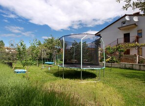 Enjoy a backyard with a trampoline, lush greenery, and a small pool.