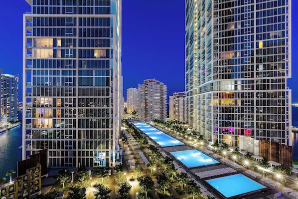 A modern high-rise hotel with multiple floors, a rooftop pool, and a waterfront view.