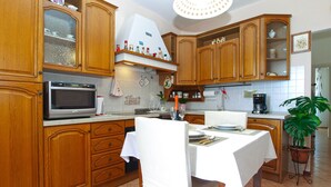 A kitchen with wooden cabinets, a microwave, a coffee maker, and a dining table set for two.