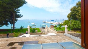A view from a balcony overlooking a marina with boats, a grassy area, and a clear sky.