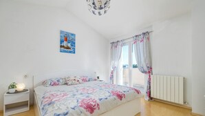 A bedroom with a bed, a nightstand, a potted plant, a painting, and a window with curtains. - Apartment 1873/23021 (Istria - Pula), 3000m from the beach (Pula)