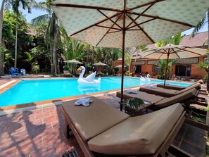 Una piscina al aire libre, sombrillas, sillones reclinables de piscina