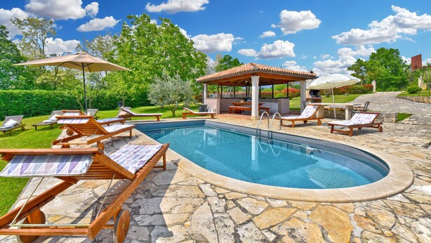 A swimming pool with lounge chairs and a covered seating area.