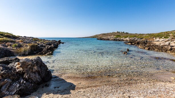 A rocky beach with clear shallow water and a distant view of the sea. - Steps from the Beach, Sunset Views to Remember! (Chania)