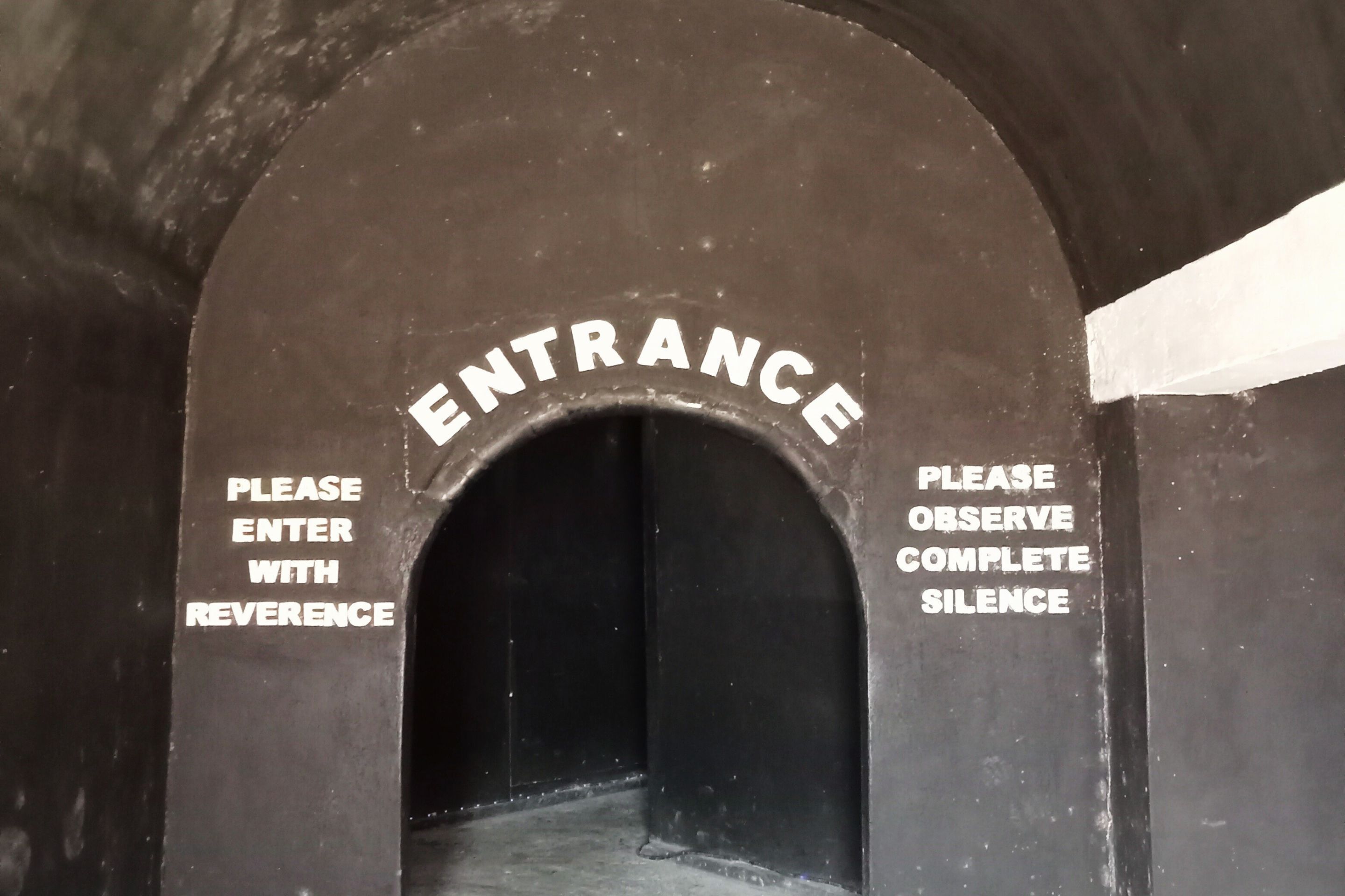 Una entrada arqueada con las palabras “ENTRANCE” y “PLEASE ENTER WITH REVERENCE” a cada lado.