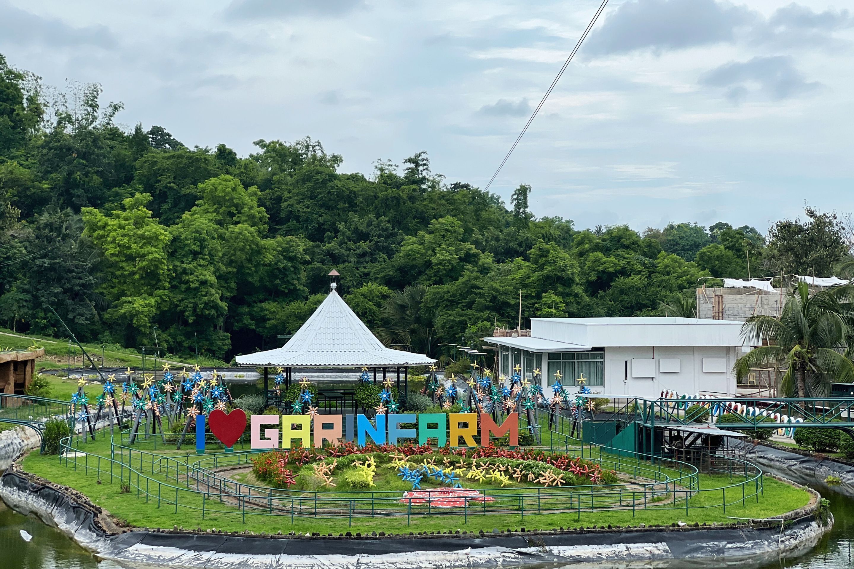 A sign with "CARINFARM" and a gazebo surrounded by greenery.