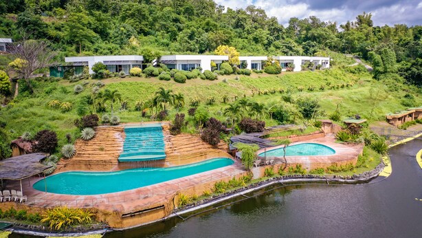 Een resort met diverse zwembaden, weelderige groene begroeiing en moderne gebouwen op een helling.