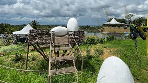 Een witte eierinstallatie in een natuurlijke omgeving met een witte tent en een gele constructie op de achtergrond.