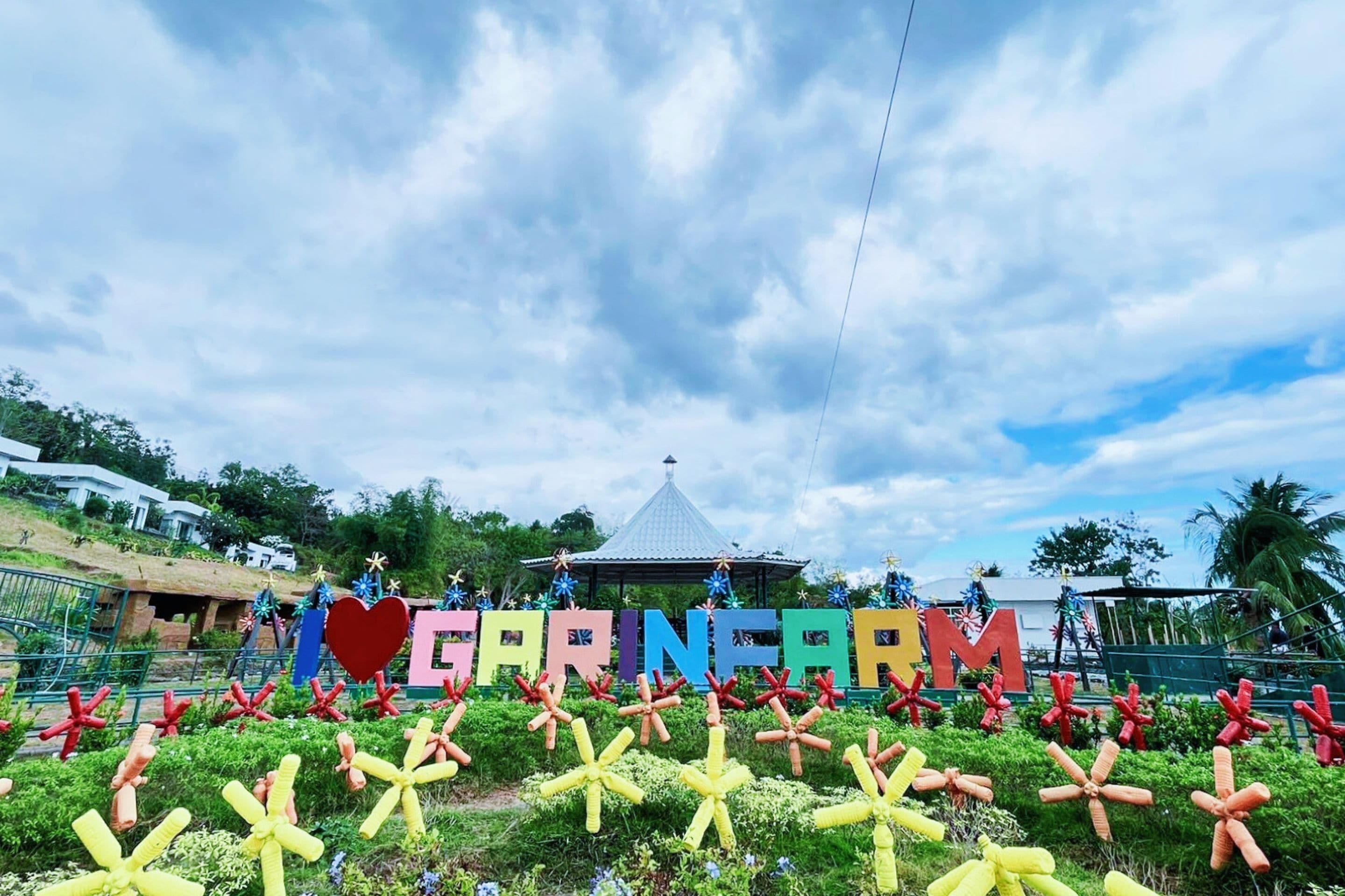 A sign with the word "CARNIVAL" and star-shaped decorations in front of a building with a thatched roof.