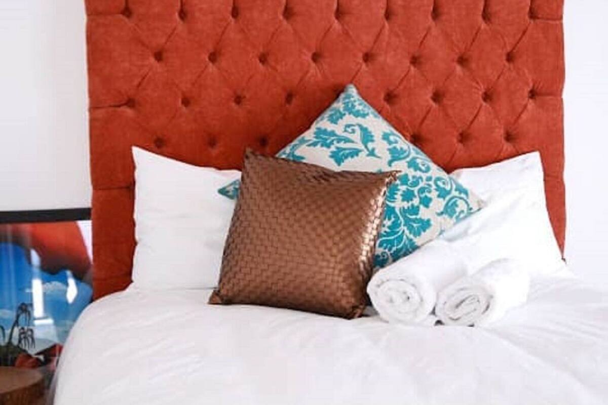 A bed with a tufted headboard, white bedding, and decorative pillows.