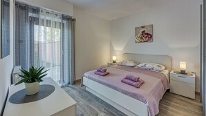 A modern bedroom with a large bed, bedside lamps, a potted plant, and a painting on the wall. - Apartment 1899/23273 (Istria - Rovinj), 1000m from the beach (Rovinj)
