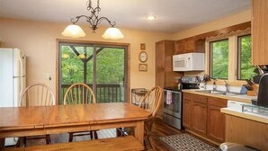 A kitchen with wooden cabinets, a microwave, and a dining table with chairs. - NF17- Cool, Creekside Home! Hot Tub! Pets ok! (Davis)