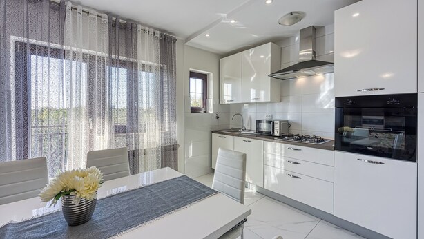 A modern kitchen with white cabinetry, a gas stove, and a built-in oven. - Apartment 1899/23274 (Istria - Rovinj), 1000m from the beach (Rovinj)