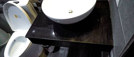 A bathroom with a white sink, a toilet, and a bidet.