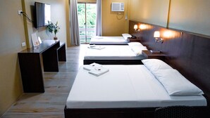 A hotel room with two beds, a desk, a TV, and a window with curtains.
