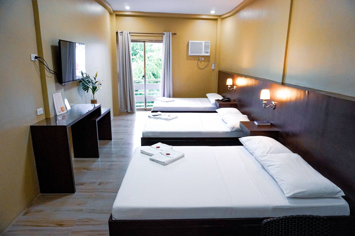 Une chambre d’hôtel avec deux lits, un bureau, une télévision et une fenêtre avec des rideaux.