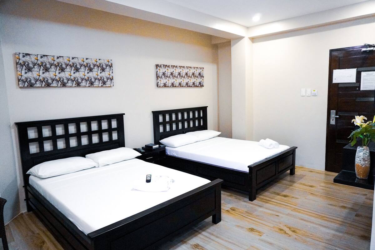 Une chambre d’hôtel avec deux lits, un plancher en bois et deux œuvres d’art accrochées au mur.