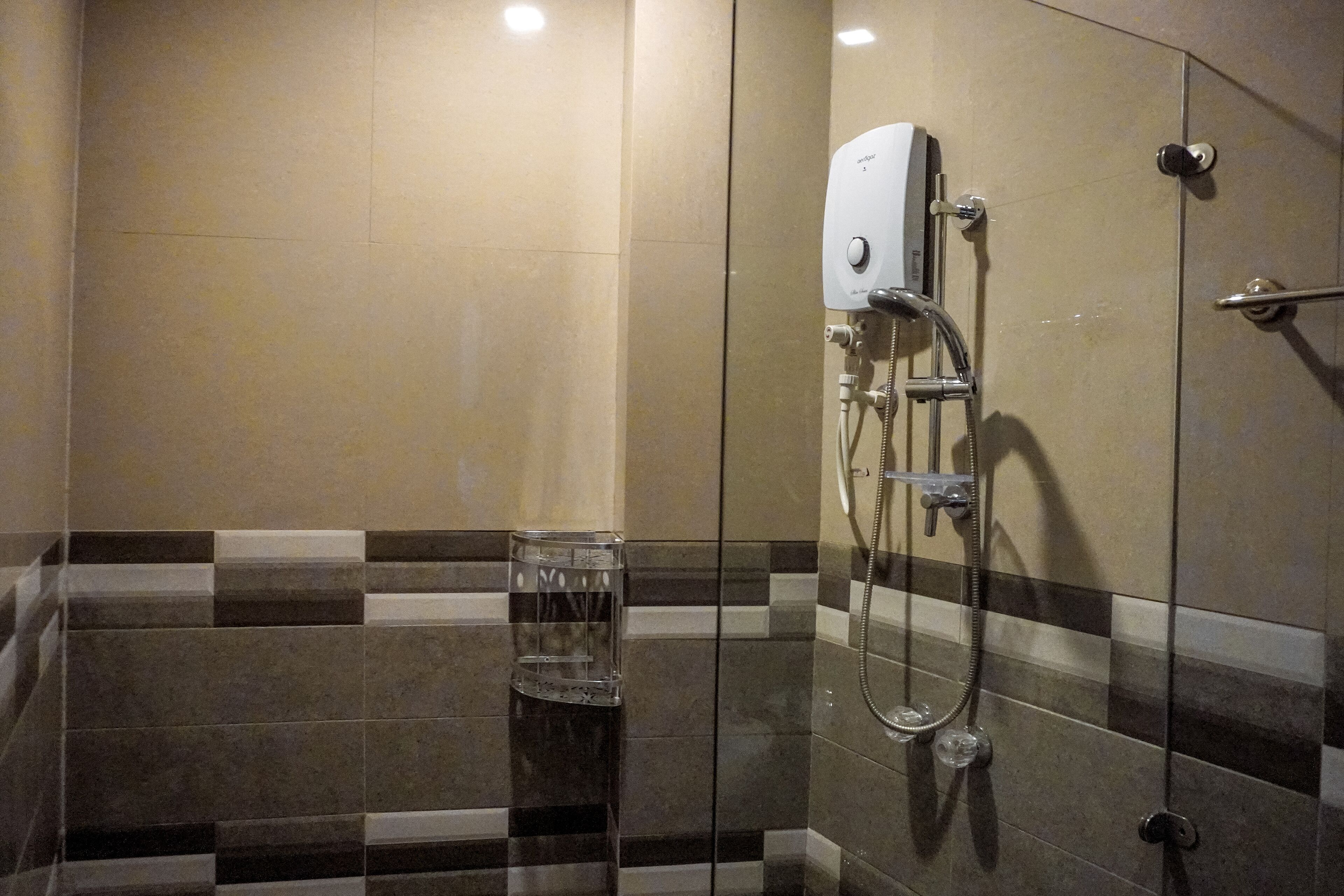 A shower with a handheld showerhead, a glass of water, and a towel rack.