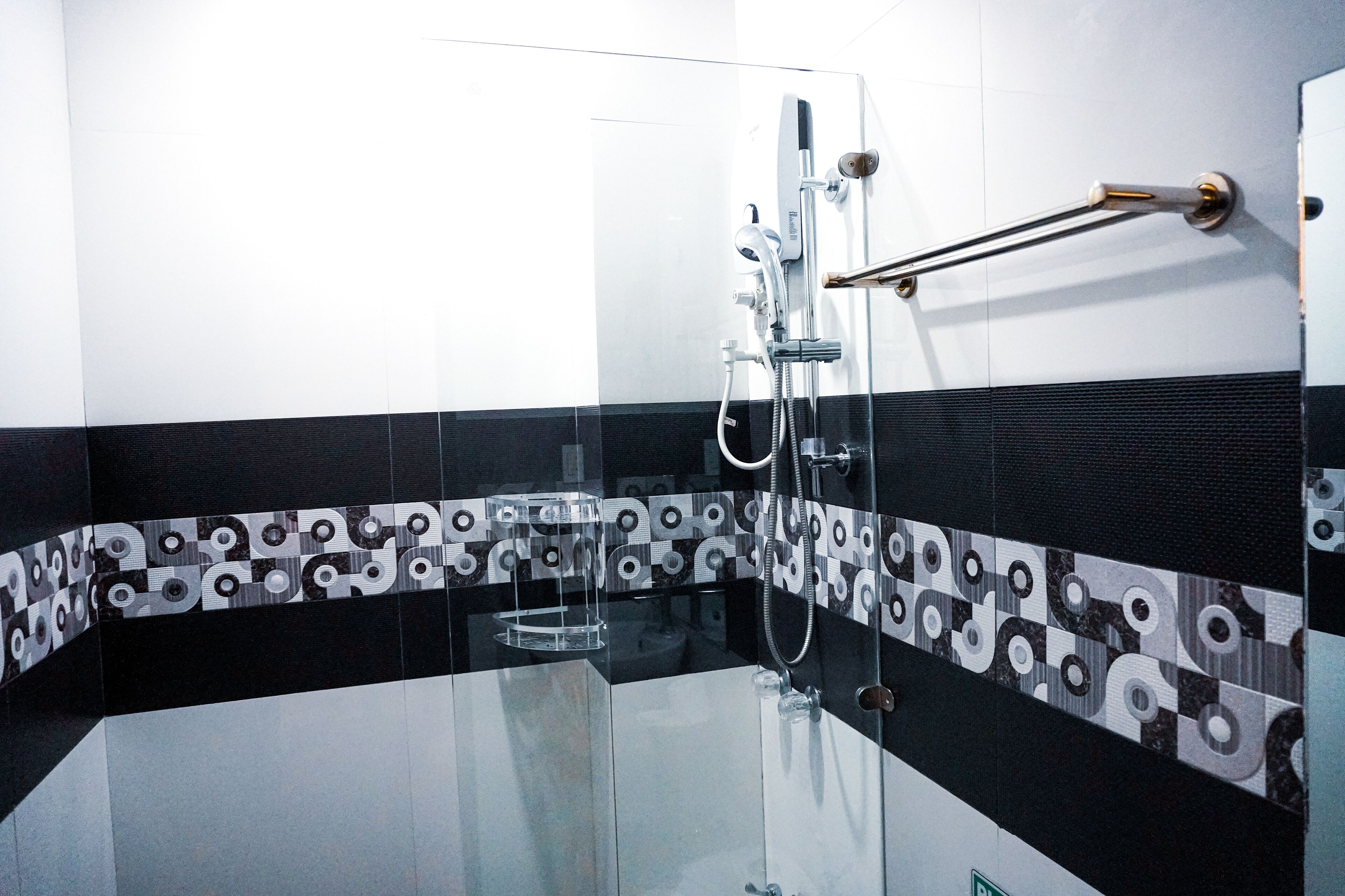 Un baño moderno con cabina de ducha de vidrio, un perchero y un salpicadero de azulejos estampados.