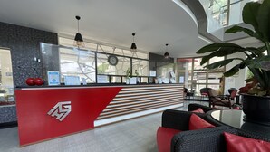 A reception area with a red counter, black wicker furniture, and a large potted plant.