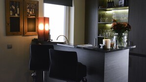 A modern kitchen with a bar area, featuring a wine rack, a vase with flowers, and a lit candle. - B & B Aphrodite (Zonnebeke)