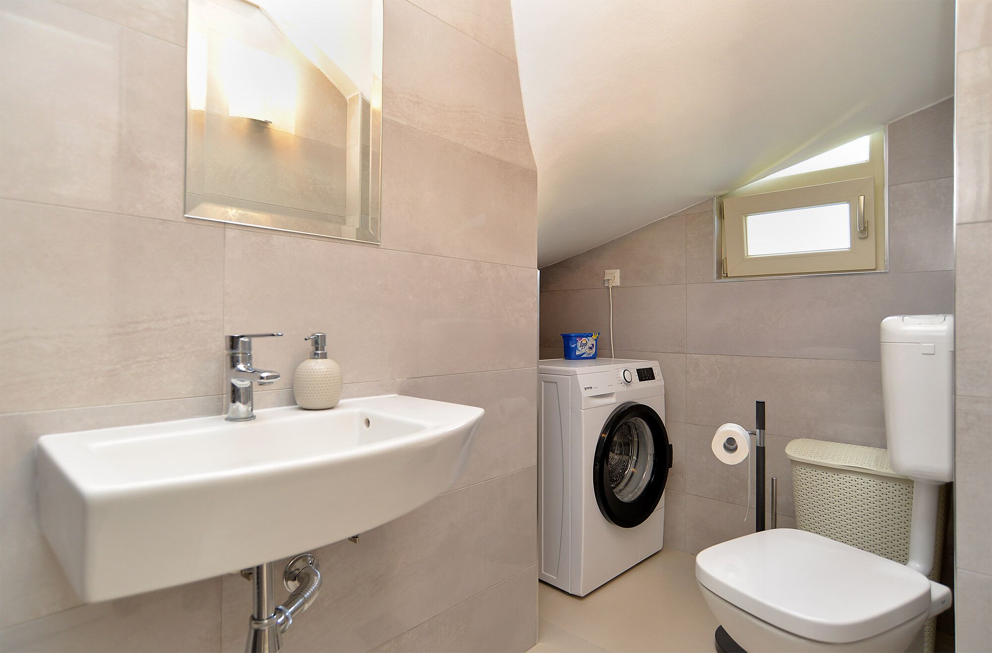 Une petite salle de bain comprenant un lavabo, des toilettes et un lave-linge.