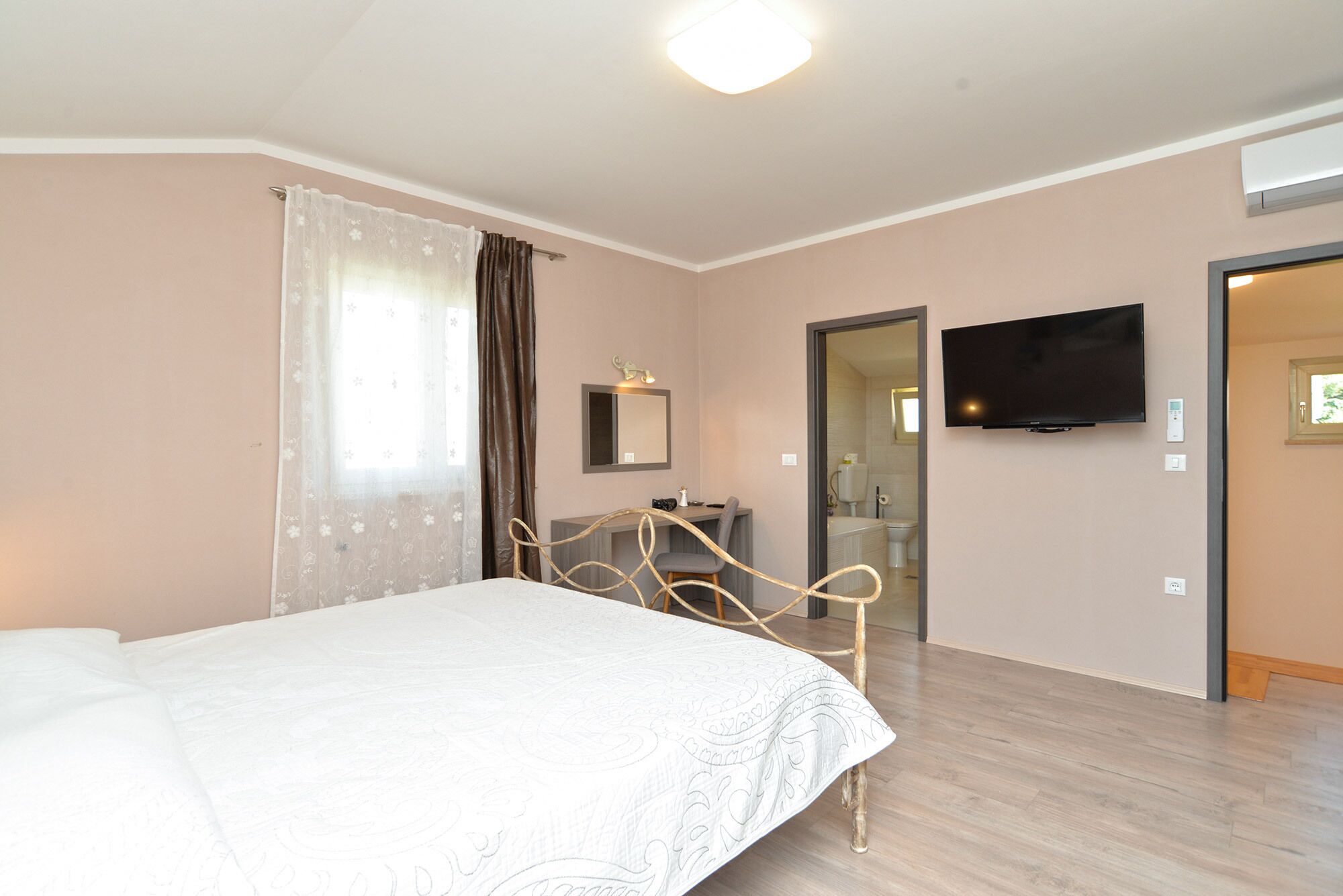 Een hotelkamer met een bed, een bureau, een stoel, een televisie en een badkamer zichtbaar door een geopende deur.