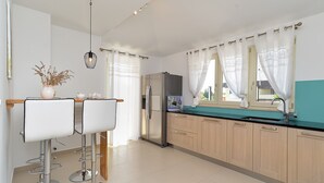 A modern kitchen with a refrigerator, double sink, and bar stools. - Villa 1924/23637 (Istria - Poreč), 3500m from the beach (Poreč)