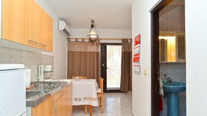 A compact kitchen with a gas stove, a coffee maker, and a dining table with a tablecloth. - Apartment 1925/23657 (Istria - Banjole), 500m from the beach (Banjole)