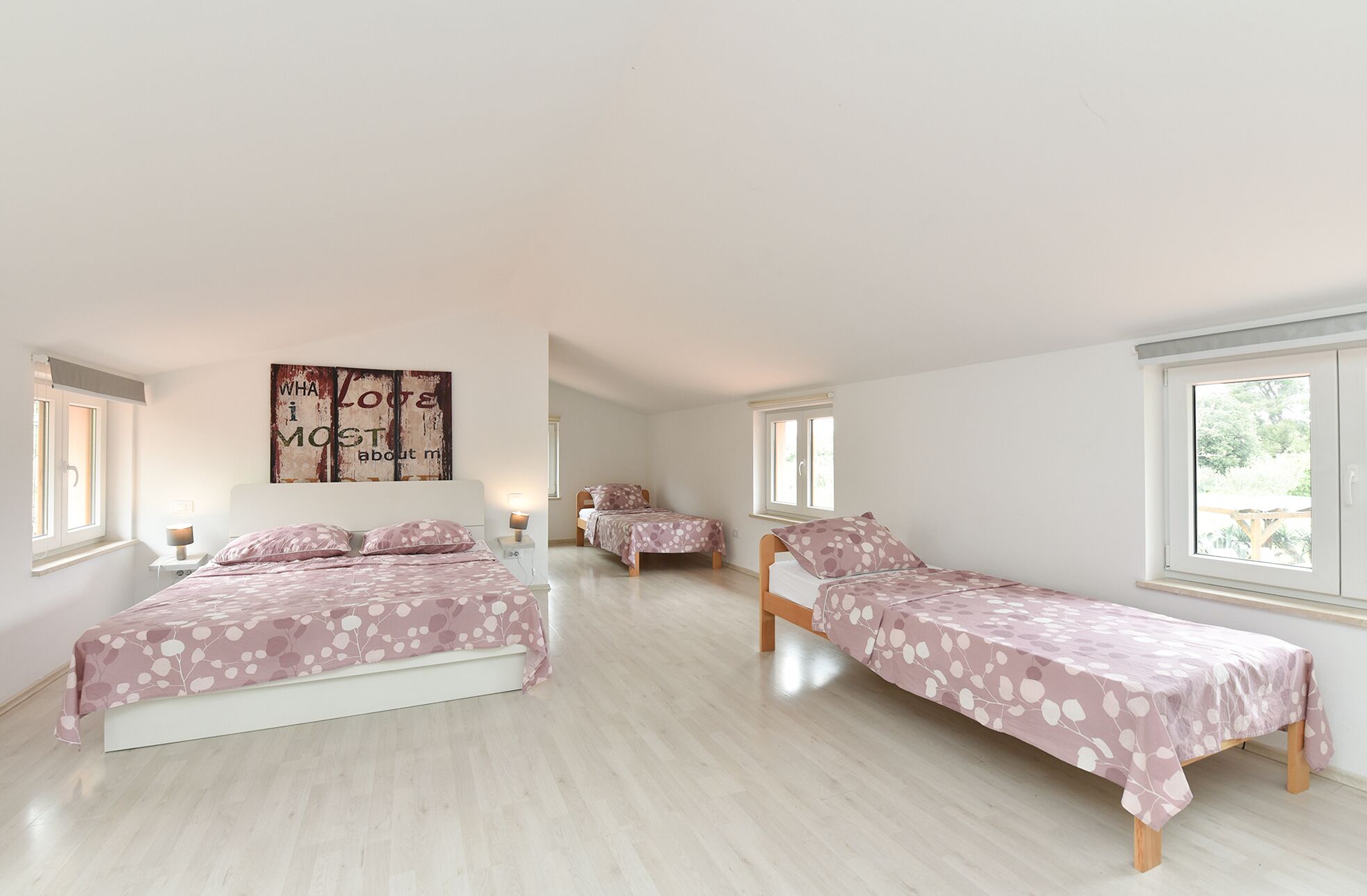 A spacious bedroom with two single beds and a large window providing natural light.