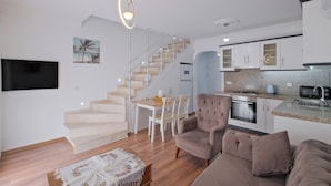 A modern apartment with a staircase leading to a loft bedroom, a dining area, and a kitchen with granite countertops.