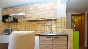 Una cucina compatta con mobili in legno, un forno a microonde e un lavandino.