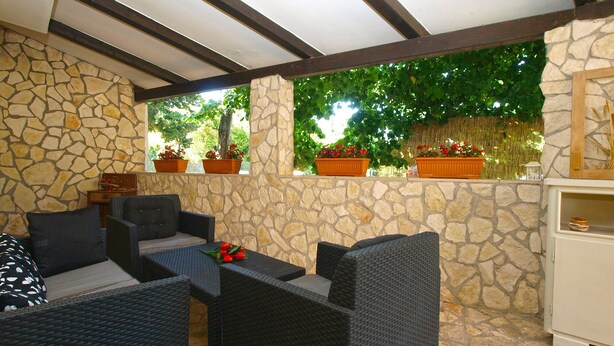 Un patio riparato con pareti in pietra, mobili in vimini e piante in vaso.