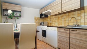 Una cucina compatta con zona pranzo, dotata di forno a microonde, forno e lavastoviglie.