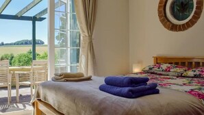 A bedroom with a bed, a window, a view of the outdoors, and a wooden bench outside. - Turpins Ride (Chalfont St Giles)