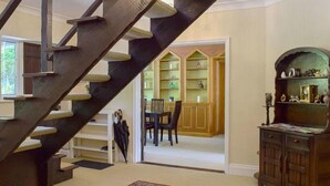 A staircase leading to a dining area with a table and chairs, a bookshelf, and a cabinet. - Turpins Ride (Chalfont St Giles)